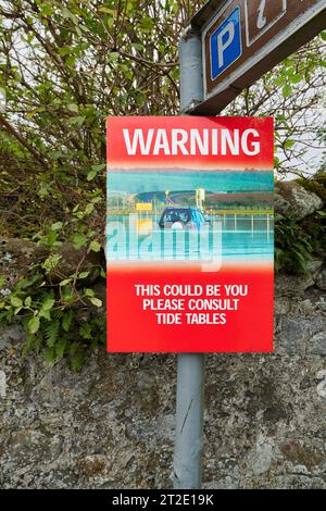 Notice board warning about crossing the causeway, when the tide is out, to and from the Holy Island of Lindisfarne, Northumberland, England. Stock Photo