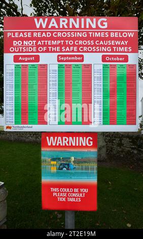 Notice board warning about crossing the causeway, when the tide is out, to and from the Holy Island of Lindisfarne, Northumberland, England. Stock Photo