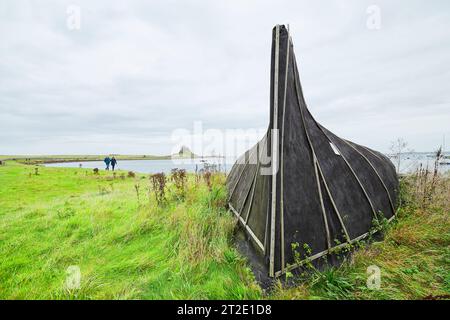 Former herring fishing boat, now upturned and used as a storage shed on the shore of the Holy Island of Lindisfarne, Northumberland, England. Stock Photo