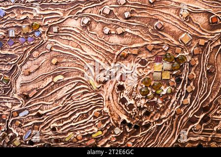 The brown texture of the concrete wall is made of decorative plaster with the addition of multi-colored gems, glass squares and circles with veins and Stock Photo