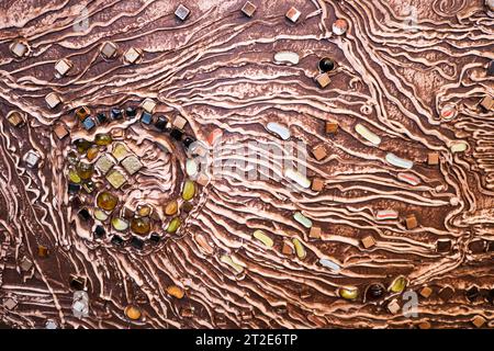 The brown texture of the concrete wall is made of decorative plaster with the addition of multi-colored gems, glass squares and circles with veins and Stock Photo