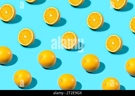 Trendy Summer food pattern made with oranges on bright light blue background. Whole and sliced oranges. Minimal summer concept. Stock Photo