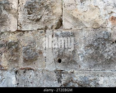 A fragment of a stone wall made of roughly hewn stone. Stock Photo