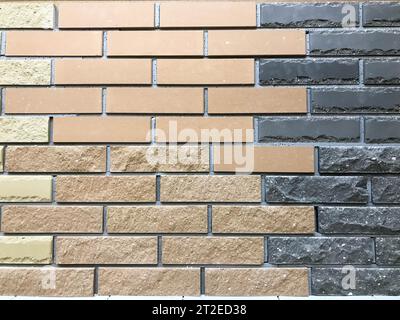 Beautiful texture of a decorative wall of two-tone building brown and black textured embossed brick with seams. The background. Stock Photo