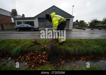 A workman clears a drainage ditch in the village of Edzell, Scotland, ahead of Storm Babet. The UK is bracing for heavy wind and rain from Storm Babet, the second named storm of the season. A rare red weather warning stating there is a 'risk to life' has been issued for parts of Scotland as the storm is expected to batter the UK on Thursday. Picture date: Thursday October 19, 2023. Stock Photo