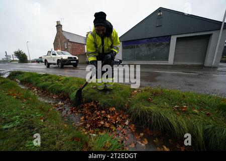 A workman clears a drainage ditch in the village of Edzell, Scotland, ahead of Storm Babet. The UK is bracing for heavy wind and rain from Storm Babet, the second named storm of the season. A rare red weather warning stating there is a 'risk to life' has been issued for parts of Scotland as the storm is expected to batter the UK on Thursday. Picture date: Thursday October 19, 2023. Stock Photo