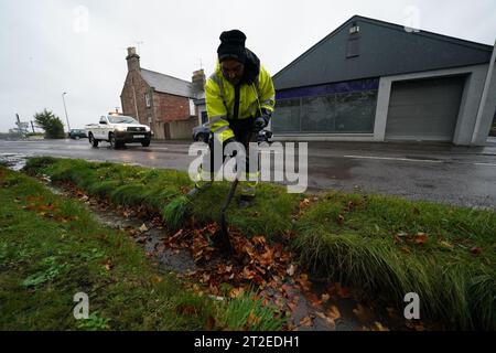 A workman clears a drainage ditch in the village of Edzell, Scotland, ahead of Storm Babet. The UK is bracing for heavy wind and rain from Storm Babet, the second named storm of the season. A rare red weather warning stating there is a 'risk to life' has been issued for parts of Scotland as the storm is expected to batter the UK on Thursday. Picture date: Thursday October 19, 2023. Stock Photo