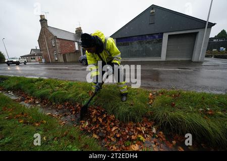 A workman clears a drainage ditch in the village of Edzell, Scotland, ahead of Storm Babet. The UK is bracing for heavy wind and rain from Storm Babet, the second named storm of the season. A rare red weather warning stating there is a 'risk to life' has been issued for parts of Scotland as the storm is expected to batter the UK on Thursday. Picture date: Thursday October 19, 2023. Stock Photo