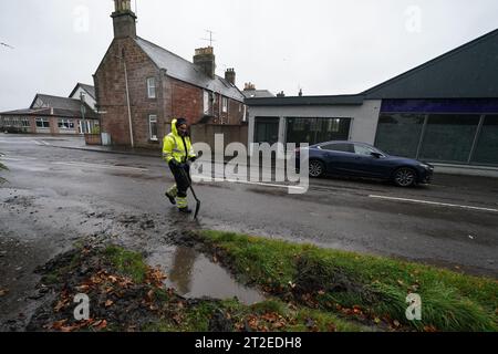 A workman clears a drainage ditch in the village of Edzell, Scotland, ahead of Storm Babet. The UK is bracing for heavy wind and rain from Storm Babet, the second named storm of the season. A rare red weather warning stating there is a 'risk to life' has been issued for parts of Scotland as the storm is expected to batter the UK on Thursday. Picture date: Thursday October 19, 2023. Stock Photo