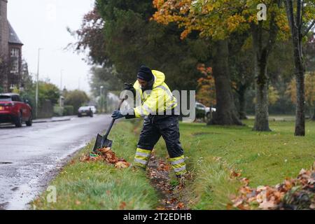 A workman clears a drainage ditch in the village of Edzell, Scotland, ahead of Storm Babet. The UK is bracing for heavy wind and rain from Storm Babet, the second named storm of the season. A rare red weather warning stating there is a 'risk to life' has been issued for parts of Scotland as the storm is expected to batter the UK on Thursday. Picture date: Thursday October 19, 2023. Stock Photo