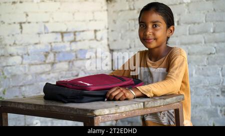 Happy Indian elementary school girls students sitting at desk in classroom with writing in notebook with pencil, Examination and test, female Educatio Stock Photo