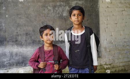 Smiling Indian Rural school boy with backpack looking at camera. Cheerful kid wearing school uniform with a big smile. Elementary and primary school e Stock Photo