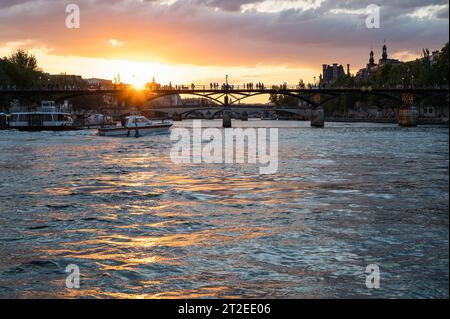 Paris, France - August 26 2022: Sunset at Bridge Pont des Arts, pedestrian bridge that has international reputation as the bridge of romance. Stock Photo