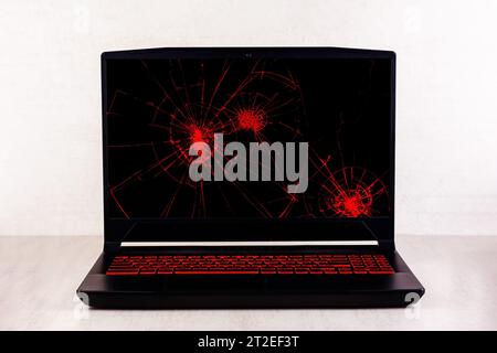 a gaming laptop with traces of bumps and cracks on a broken screen on a light gray background close up front view Stock Photo