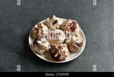 Chocolate meringue cookies on plate over dark stone background. Close up view Stock Photo