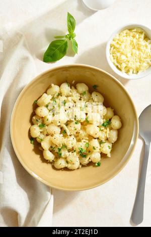 Potato gnocchi with parmesan cheese and greens in bowl over light background. Top view, flat lay Stock Photo