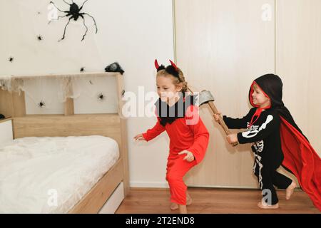 Children in skeleton and witch costume laughing at home halloween Stock Photo