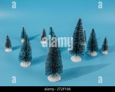 The photo shows several decorative artificial Christmas trees located on a bright blue background. The blue background creates a beautiful contrast an Stock Photo