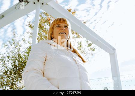 Portrait red-haired middle-aged woman against blurred cityscape background Stock Photo