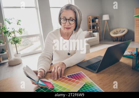Photo of pretty shiny elderly lady wear white choosing renovation walls colors indoors apartment room Stock Photo