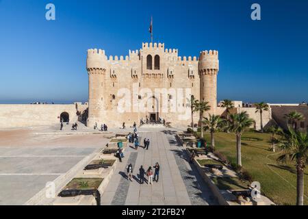 Alexandria, Egypt - December 14, 2018: People walk in front of The Citadel of Qaitbay or the Fort of Qaitbay. It is a 15th-century defensive fortress Stock Photo