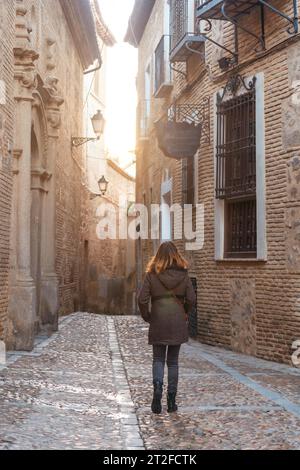 A tourist walking at sunset in the medieval city of Toledo in Castilla La Mancha, Spain Stock Photo