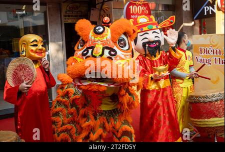 A group of Vietnamese actors and musicians in colourful costumes perform a traditional lion dance for a business as it reopens after Tet, or the lunar Stock Photo