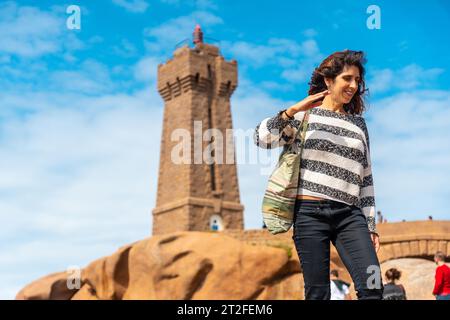 A young woman at the Mean Ruz Lighthouse, port of Ploumanach, in the town of Perros-Guirec in the Cotes-d'Armor department, in French Brittany, France Stock Photo