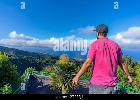 A young man in a pink t-shirt on top of the mountain at the viewpoint of the Cubo de la Galga natural park on the northeast coast on the island of La Stock Photo