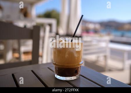 https://l450v.alamy.com/450v/2t2ffxk/view-of-an-iced-greek-coffee-also-known-as-freddo-cappuccino-with-a-straw-and-the-beach-of-gialos-in-ios-greece-2t2ffxk.jpg