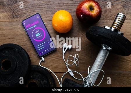 Top view of workout and fitness dumbbell, fresh fruit and smartphone showing health and fitness app in the screen. Wellness, diet and home bodycare co Stock Photo