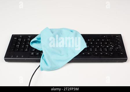 Cleaning computer keyboard in office with a rag cloth, dusty and dirty electronic, housework Stock Photo