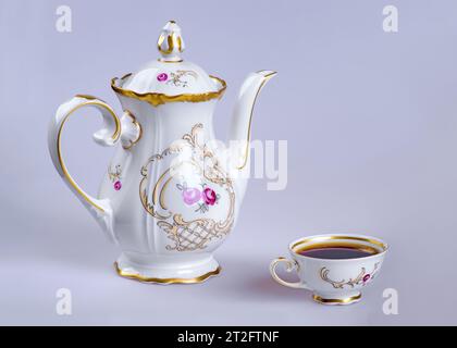 A pottery kettle and a cup filled with coffee (tea) on a gray background. Stock Photo