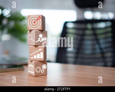 Wooden blocks and business icons on table wood represent the concept of business strategy and setting business goals. Stock Photo