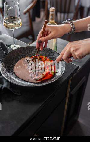 Sea bass or dorado fillet with sweet potato puree and flying fish roe sauce on a black plate in a restaurant Stock Photo
