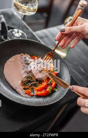 Sea bass or dorado fillet with sweet potato puree and flying fish roe sauce on a black plate in a restaurant Stock Photo