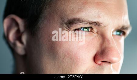 Squinting eyes of a man looking at screen. Poor eyesight, bad vision. Light from laptop computer or phone. Guy watching tv. Focus on work. Stock Photo