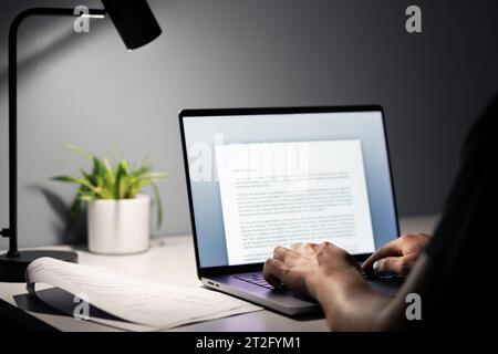 Man writing text document, essay or letter with laptop. Freelance writer, journalist or entrepreneur working late at night, overtime. Stock Photo