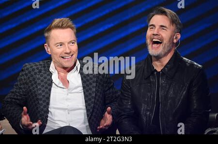 Leipzig, Germany. 18th Oct, 2023. Irish singer Ronan Keating (l) and Gary Barlow from the British pop group Take That laugh together in the 'Your Songs' show in Leipzig. Mitteldeutscher Rundfunk recorded the music show with big names. The artists perform their big hits alongside new songs in a live atmosphere, accompanied by a studio band and the 40-piece MDR Symphony Orchestra. On December 15, 'Your Songs' will be broadcast on the German public broadcaster Ersten and will be available in advance in the Mediathek from December 8. Credit: Hendrik Schmidt/dpa/Alamy Live News Stock Photo