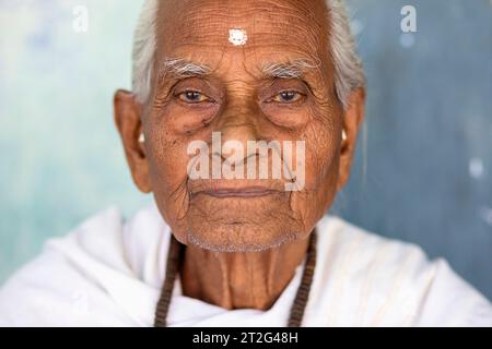 A portrait of the oldest Hindu monk in traditional clothes at the Uttar Kamalabari Hindu monastery, Majuli Island, Assam, India Stock Photo