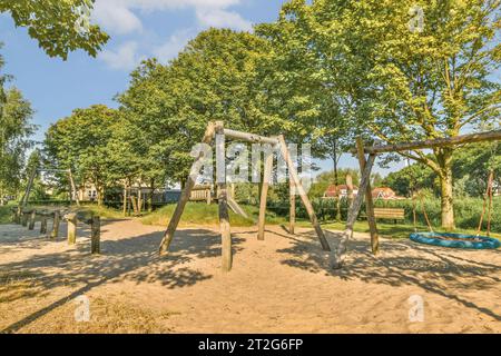 a playground area with swings, slides and slides in the sand at an outdoor play area surrounded by trees Stock Photo