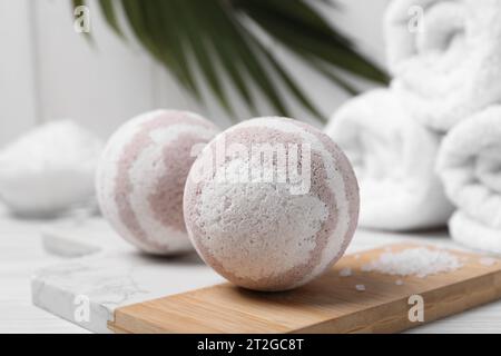 Bath bombs, sea salt and rolled towels on white wooden table, closeup Stock Photo