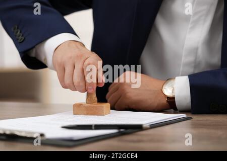 Man stamping document at table, closeup view Stock Photo