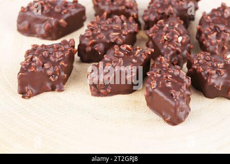Chocolate with hazelnuts on beige wooden board. Stock Photo