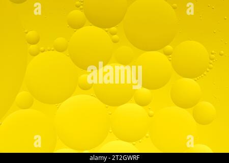 Macro photo with circles oil droplets water surface. Abstract yellow background with oil bubbles Stock Photo
