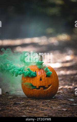 close up of a carved pumpkin for halloween with smoke coming out of the cut outs in a natural spooky forest setting Stock Photo