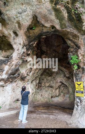 Antalya, Turkey - March 27, 2023. Karstic formations around the Upper Duden Waterfall in Antalya, Turkey. View with a ‘bat habitat’ sign and a tourist Stock Photo