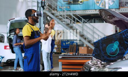 Serviceman in car service using advanced virtual reality technology to visualize motor turbine in order to fix it. Garage professional wearing VR glasses while servicing malfunctioning vehicle Stock Photo
