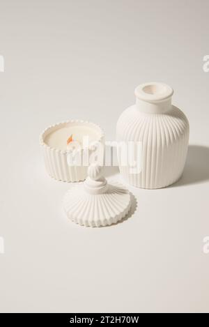 candle in white ceramic pot on a white background ,a vase with a candle.Cozy home natural eco decor Stock Photo
