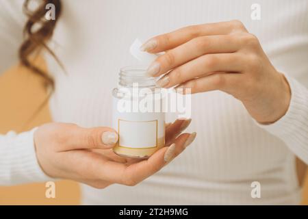 A woman is holding a bottle with pills or vitamins. Mockup, close-up. Stock Photo